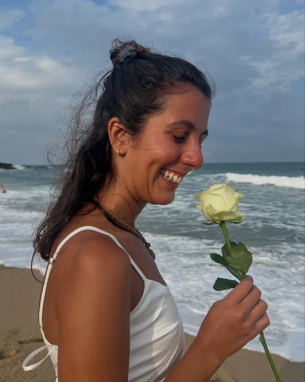 Sofía Cenni sonriendo con una rosa blanca frente al mar